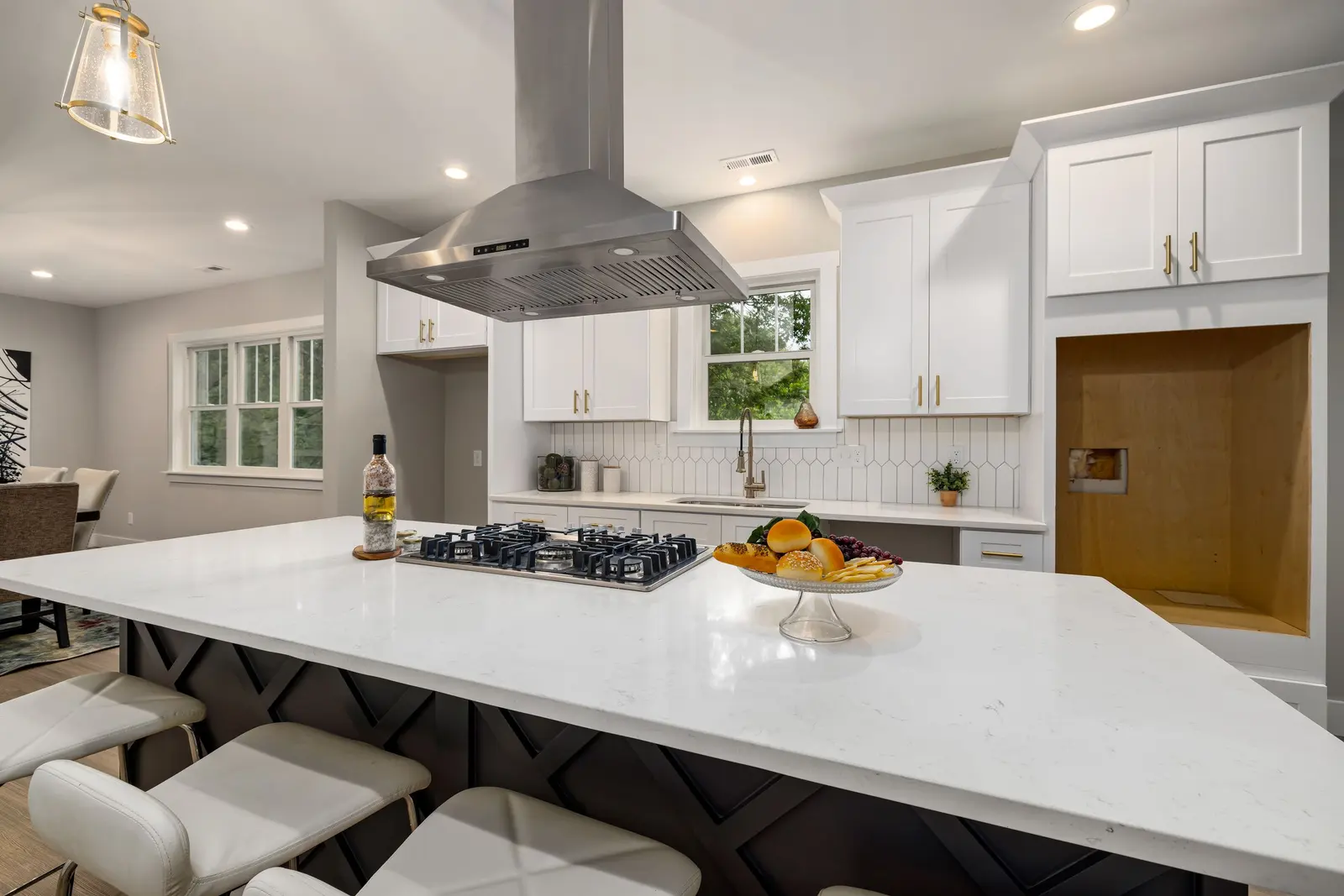 A modern kitchen with white cabinets, a large island and a stainless steel range hood.