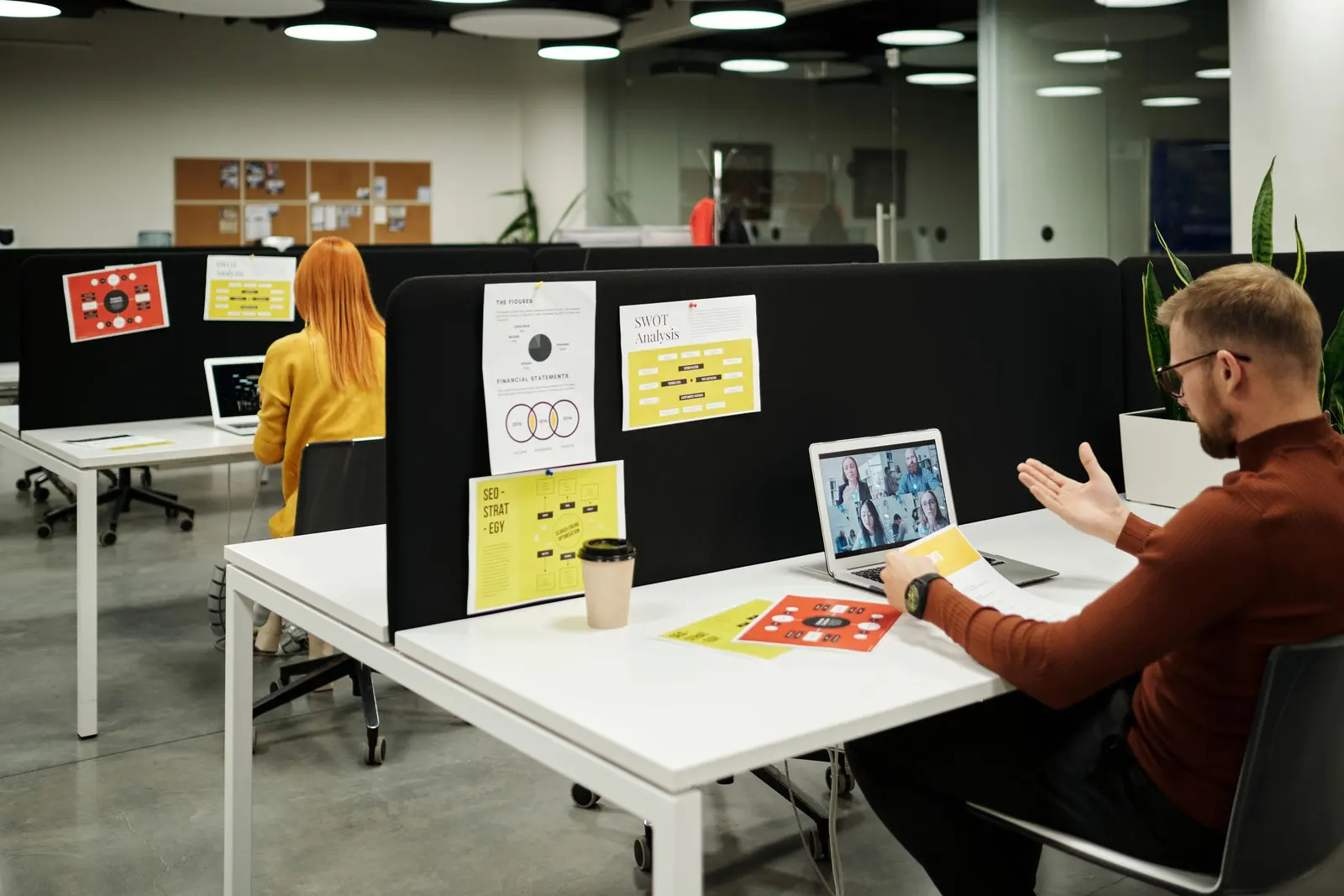 An open-plan office interior with white walls, desks and workstation dividers.
